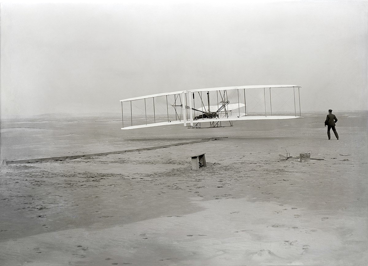 The Wright Brothers' first powered flight, December 17, 1903, at Kitty Hawk, North Carolina. Photo by John T. Daniels. Public domain, via Wikimedia Commons.